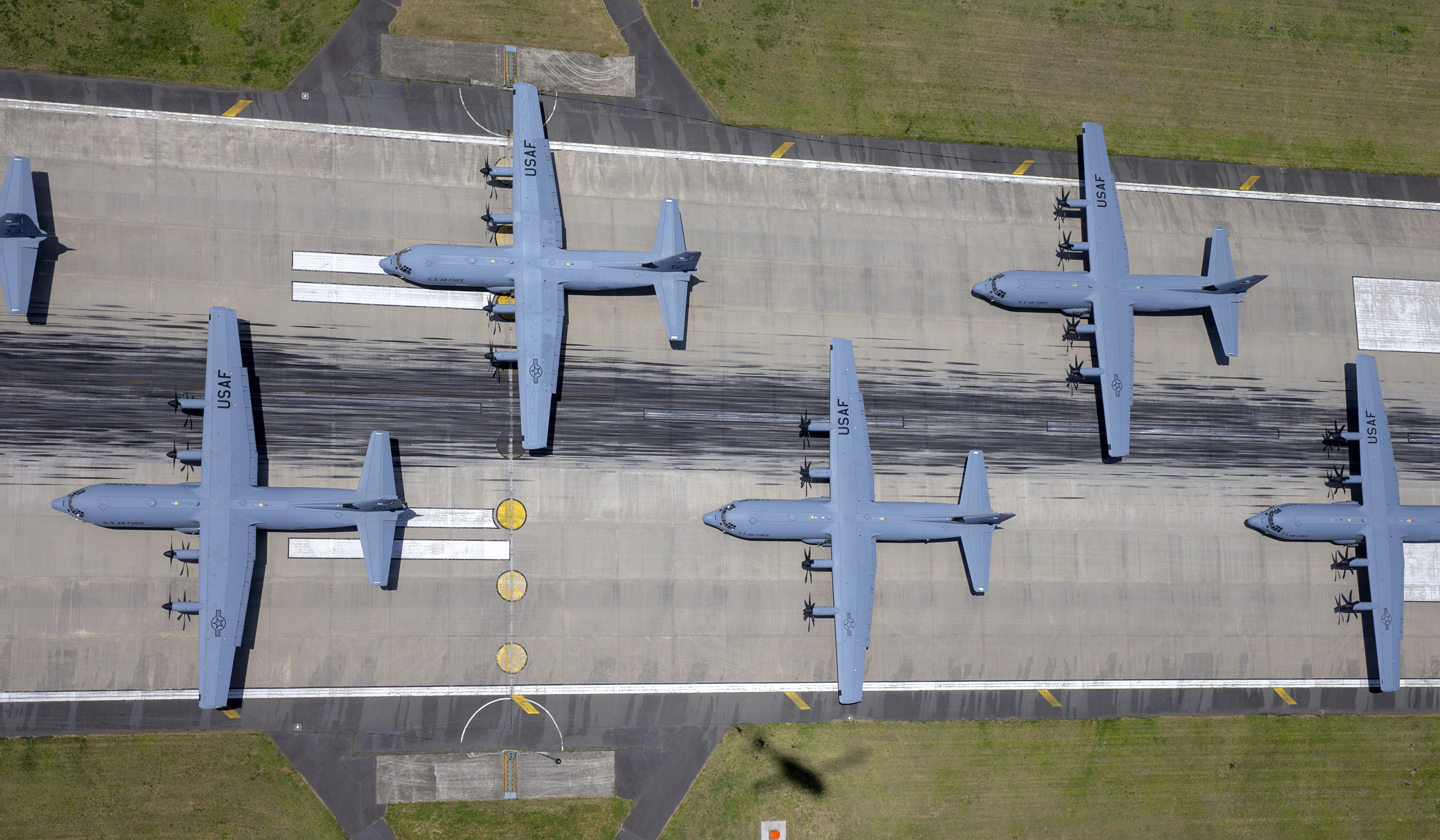 USAF cargo planes in formation on a runway.